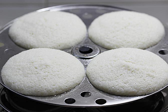 placing the plates inside a steamer to make soft idli recipe