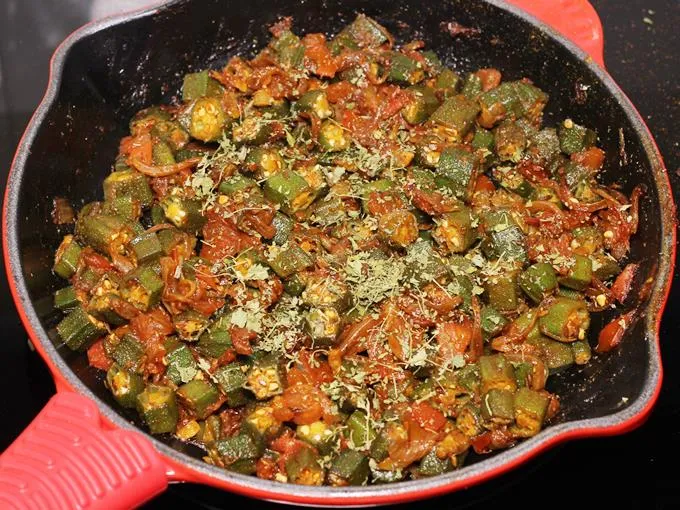 sprinkling kasuri methi to make bhindi ki sabji