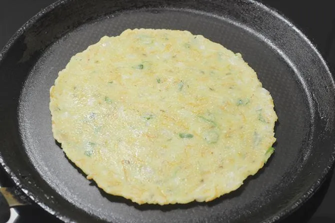 flipping and toasting akki roti on a tawa