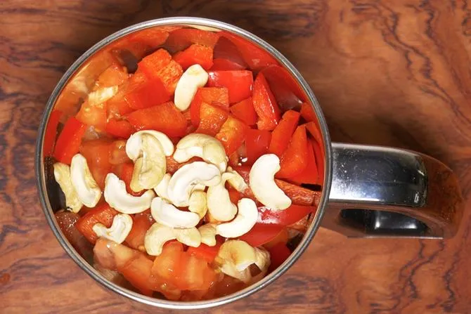 adding tomatoes cashews capsicum to make paneer do pyaza