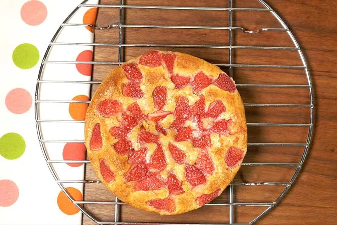 cooling eggless strawberry cake on a wired rack