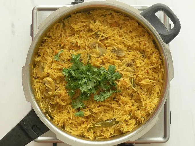 adding coriander leaves to make mushroom biryani