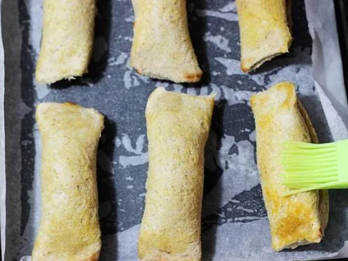 brushing butter over baked bread rolls