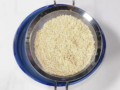 draining quinoa in a colander to make pulao