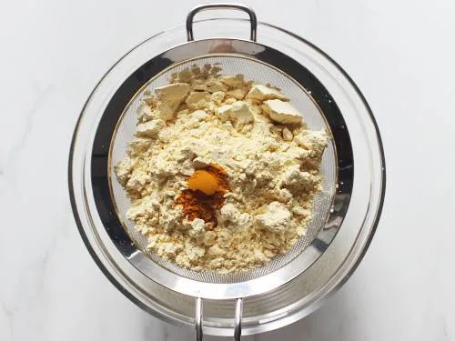 sieve besan and turmeric to make dhokla 