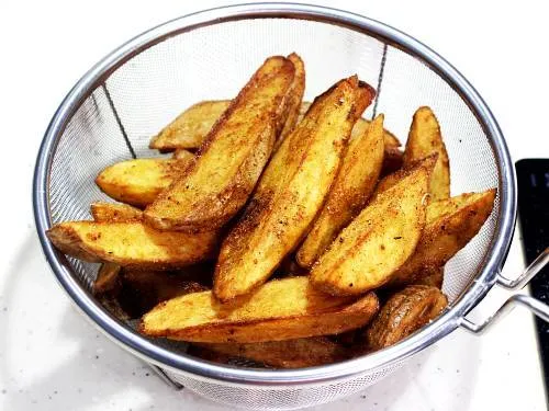 fried potato wedges in a colander ready to serve