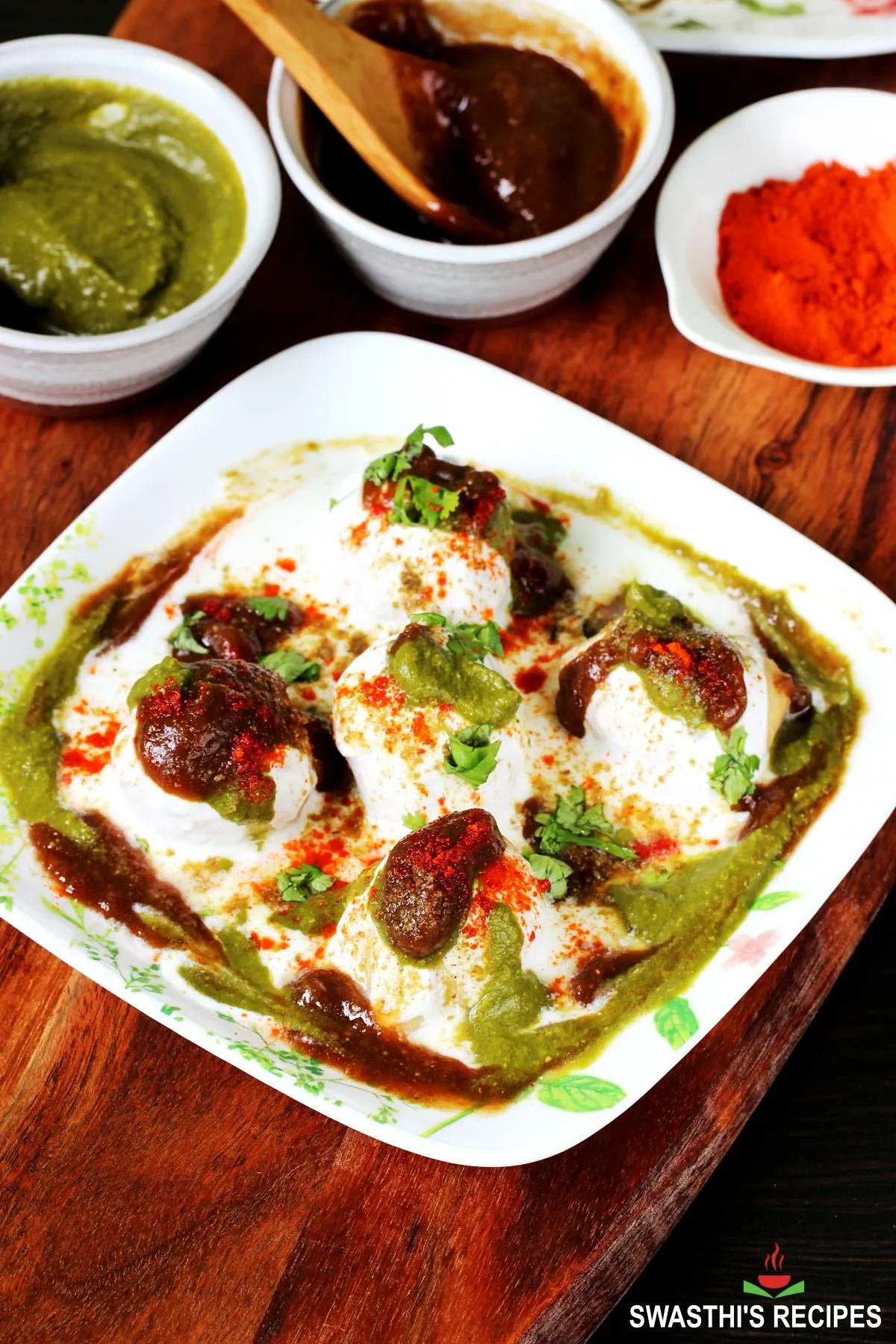 Dahi vada garnished with spice powders, coriander leaves and chutney