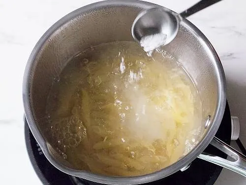 adding salt to a pot of boiling water