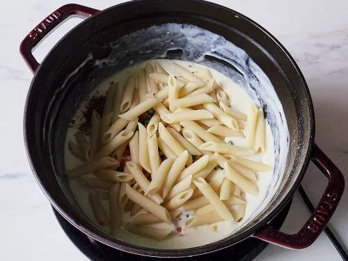 cooked pasta in white sauce with vegetables