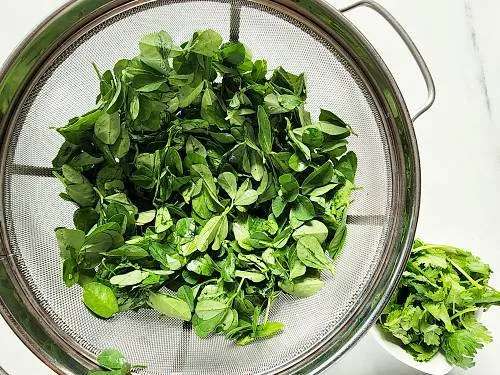 methi leaves left in a colander to drain