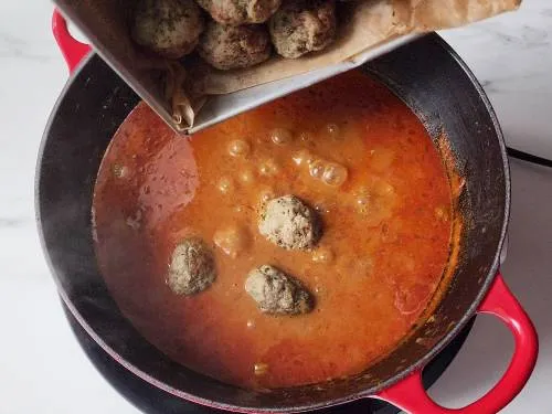 adding kofta to curry